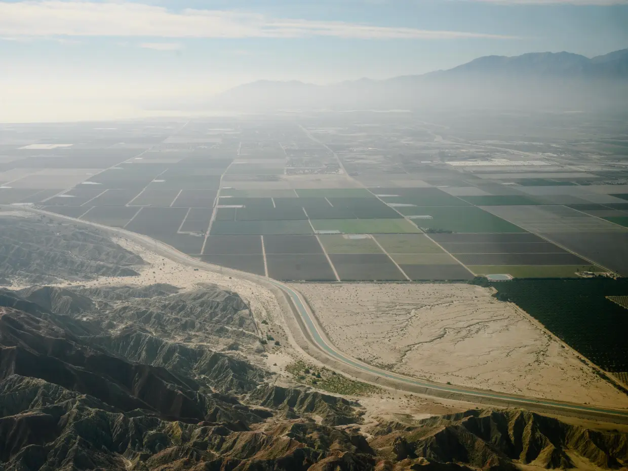 A canal winds between farmland and the mountains in the Coachella Valley on February 15, 2024.