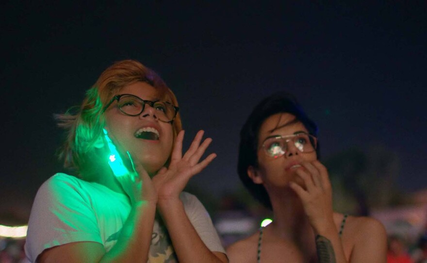 Silvia Del Carmen Castaños (left) and Estefanía “Beba” Contreras (right) watch 4th of July fireworks at night in a scene from "Hummingbirds."