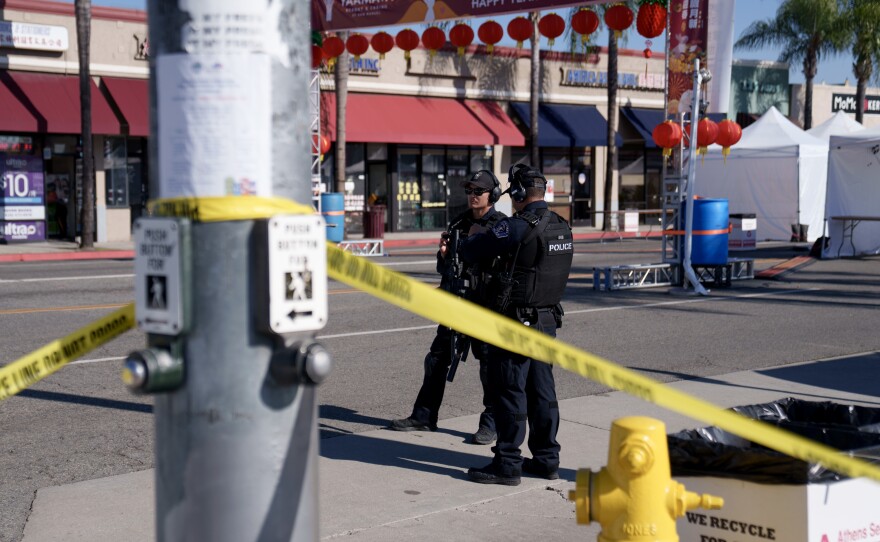Police officers stand guard near the scene of a deadly shooting on Sunday in Monterey Park, Calif. 10 people were killed and 10 more were injured at a dance studio near a Lunar New Year celebration on Saturday night.
