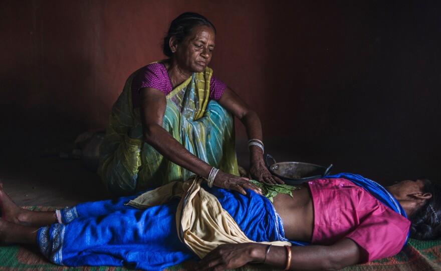 Sonpati, 55, a midwife in Salihatu Village uses warm  herbs and sand to massage tje belly — her method of carrying out an abortion and also treating abdominal pain.