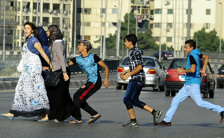 A youth, trailed by his friends, gropes a woman as she crosses a street in Cairo, Egypt.