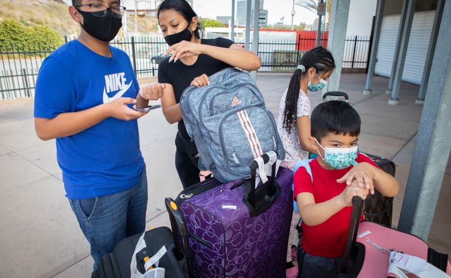 Michelle Arenas waits with her three children for a shuttle bus to Las Vegas at the San Ysidro Transit Center, June 6, 2020. The family began their day of travel in Michoacán, where they were attending a wedding.