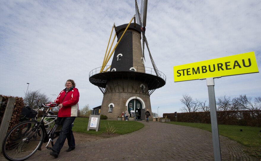 At the Kerkhovense Molen, a windmill turned polling station in Oisterwijk in south central Netherlands, a woman leaves after casting her ballot Wednesday.