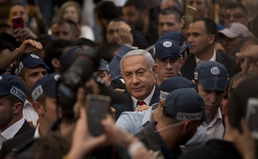 Israeli Prime Minister Benjamin Netanyahu, center, is escorted by security guards during a visit to the Hatikva market in Tel Aviv on Tuesday.