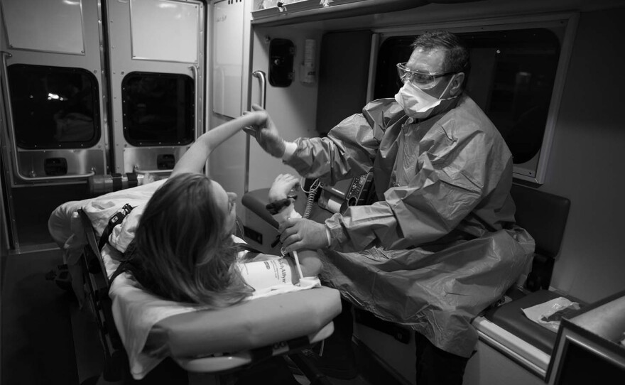 Doug Neal tries to calm a patient in an ambulance in May of 2020.