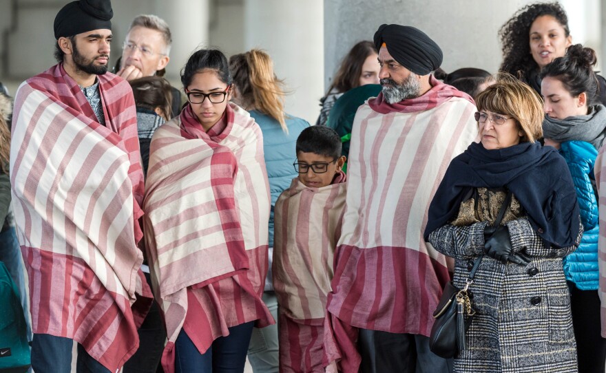 People stand near the Brussels airport after being evacuated following explosions that rocked the facility earlier today.