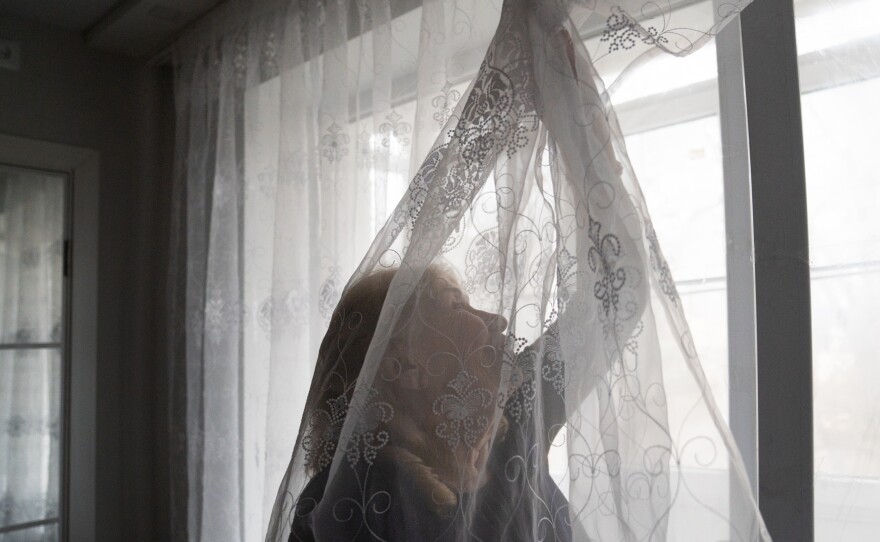 Liubov Lada arranges the curtains in the apartment she and her husband moved to after Russian shelling destroyed their old apartment.