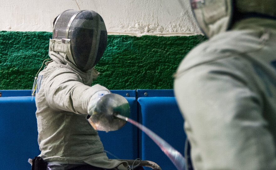 Panos Triantafyllou (left), in his fencing uniform and mask, trains with Vasilis Ntounis, his fellow Paralympic athlete and close friend.