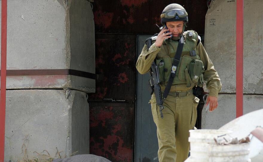 An Israeli soldier walks in front of the body of one of two guards who army sources said were killed by Palestinian militants on April 25, 2008. One of those killed was Eli Wasserman, 51.