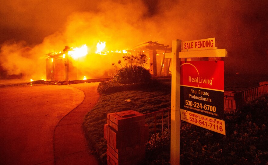 A real estate sign is seen in front of a burning home during the Carr Fire in Redding, Calif., in 2018. More than 1,600 buildings reportedly were destroyed.