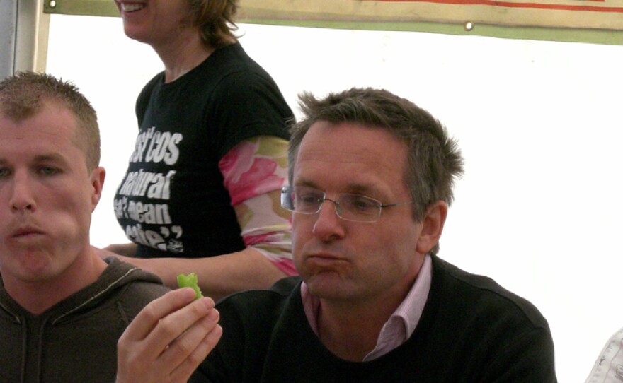 Presenter Michael Mosley takes part in a chili-eating competition to discover where pleasure meets pain. Competition organizer Miranda Pellew is seen in the background, and fellow competitor Gary Cox is next to Michael.