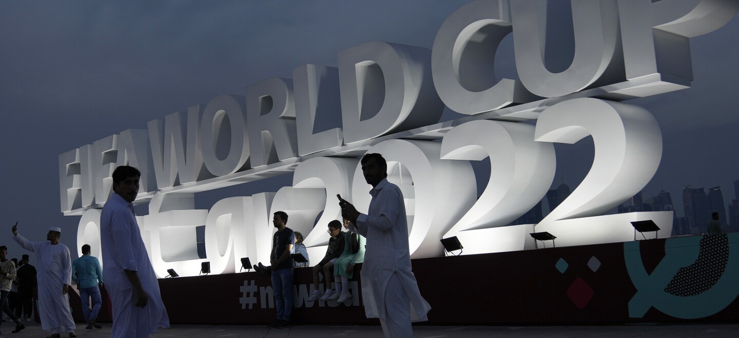 People pose for a photograph with a sign reading in English" Fifa World Cup, Qatar 2022" at the corniche in Doha, Qatar, Thursday, Nov. 17, 2022. Final preparations are being made for the soccer World Cup which starts on Nov. 20 when Qatar face Ecuador.