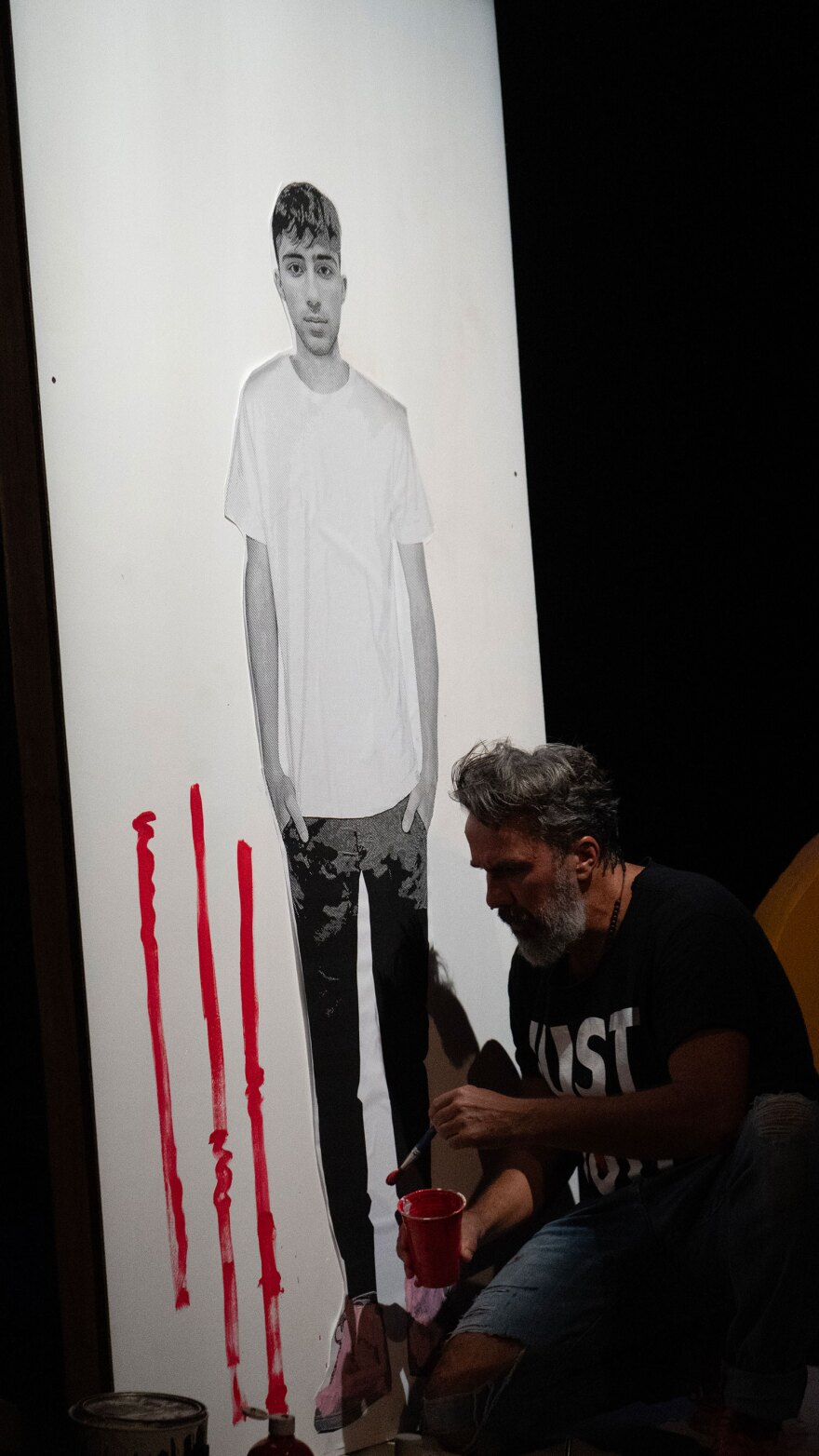 On stage, Manuel Oliver paints around and interacts with a life-size photograph of his son, Joaquin "Guac" Oliver, who was killed in the Parkland school shooting in 2018.