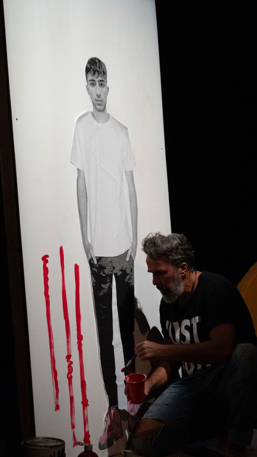 On stage, Manuel Oliver paints around and interacts with a life-size photograph of his son, Joaquin "Guac" Oliver, who was killed in the Parkland school shooting in 2018. 