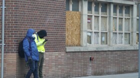 A pair of workers wear masks while waiting for a ride outside a construction site late Monday, Dec. 28, 2020, in downtown Denver. 