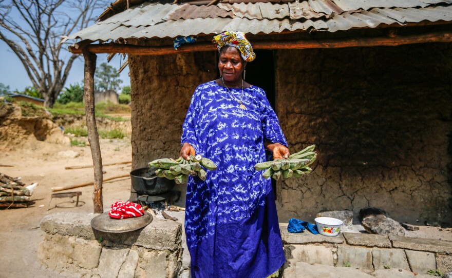 Mamuedeh Kanneh holds up bunches of unripe bananas for a photograph. Ebola is gone, but food is scarce.