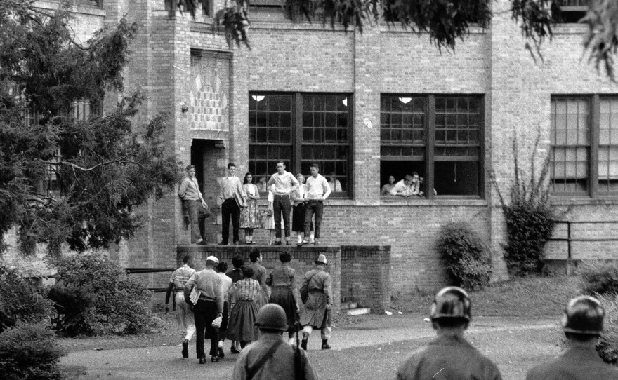 In this photo from Oct. 15, 1957, seven of nine Black students walk onto the campus of Central High School in Little Rock, Ark., with a National Guard officer as an escort and as other troops watch.