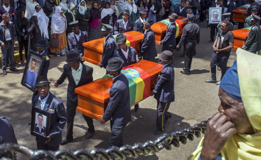 Relatives grieve next to empty caskets draped with the national flag at a mass funeral at the Holy Trinity Cathedral in Addis Ababa, Ethiopia Sunday, March 17, 2019.