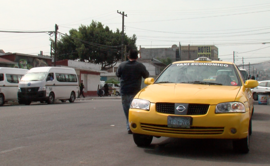 A pedestrian passes a lone yellow cab in Tijuana, July 20, 2017.