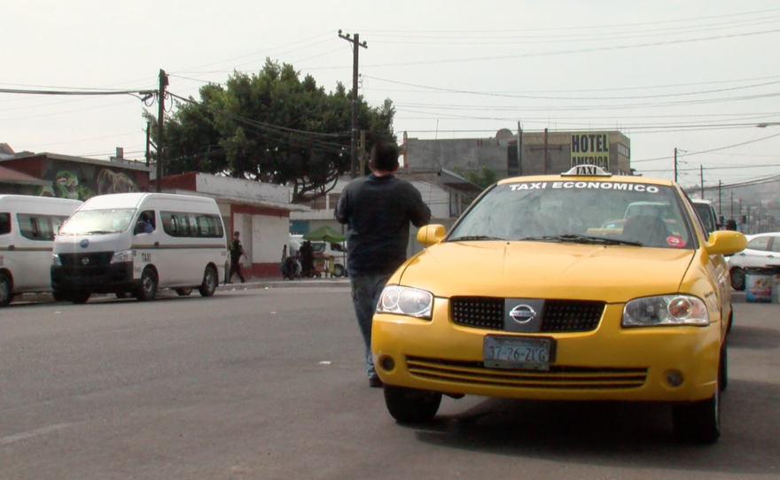 A pedestrian passes a lone yellow cab in Tijuana, July 20, 2017. 