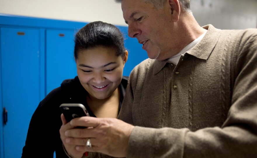 John Vowell (right) shows Tiasa Cantrell, 13, photos on his phone. Cantrell comes to Major Chords for Minors to hang out with John and Katrina while her twin sister takes guitar lessons.