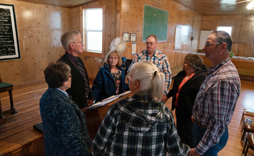Ranchers gather with traveling pastor Hal DeBoer for a religious service at First Creek Community Hall.