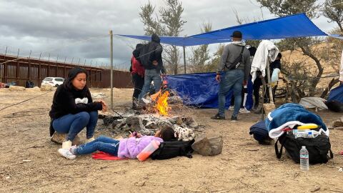 A migrant mother and child sit around a fire at a makeshift camp near the border fence in Jacumba, California on Nov. 15, 2023. 