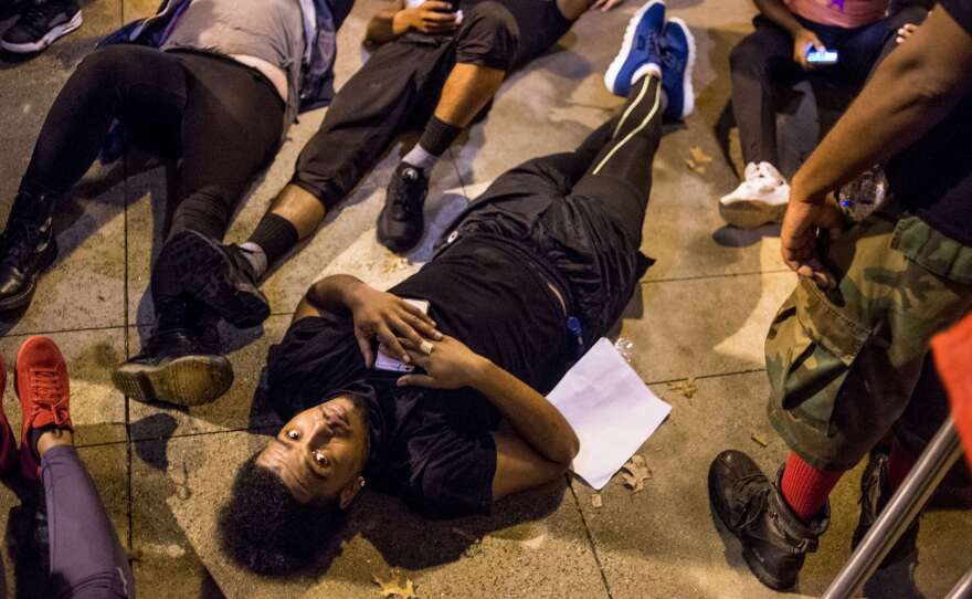 Demonstrators lie on the ground as they protest in front of the police station Thursday night in Charlotte, N.C. After two nights of violent unrest, protests on Thursday night were mostly peaceful, with no injuries or arrests reported.