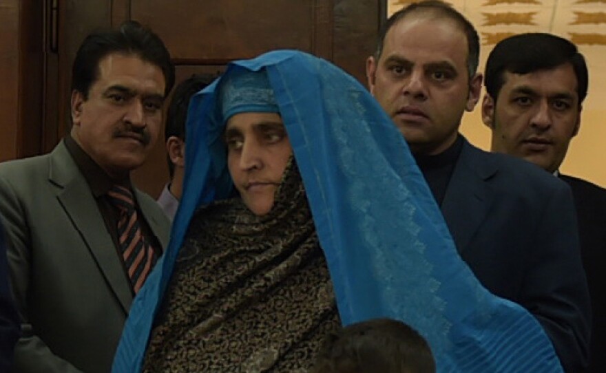 Afghan refugee Sharbat Gula (center) will get free medical care in India. She seen here arriving with her son at the Presidential Palace in Kabul before meeting with Afghan President Ashraf Ghani Wednesday.
