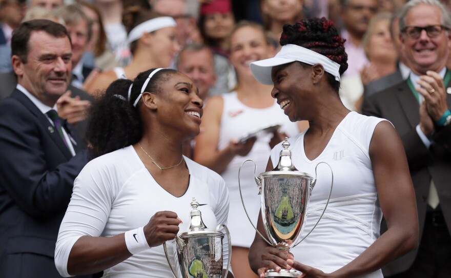 Serena Williams, left, and Venus Williams hold their trophies after winning the women's doubles final against Yaroslava Shvedova of Kazahkstan and Timea Babos of Hungary on day 13 of the Wimbledon Tennis Championships in London on Saturday.