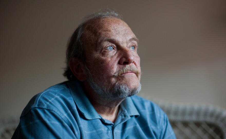 Tom Wall sits in his bedroom before the Make Room concert begins on Jan. 18. Around 20 people gathered in Wall's small apartment to attend the concert and to help him, and others like him, pay the rent.