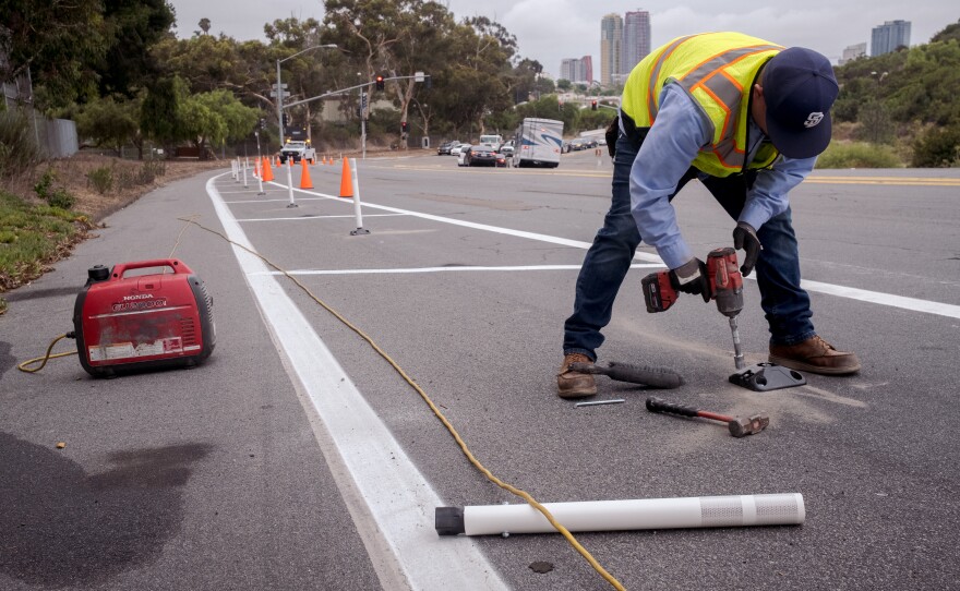 A San Diego city worker drills into the road at the spot a bollard is going to be installed on Pershing Dr., San Diego, Calif. Sept. 24, 2021.