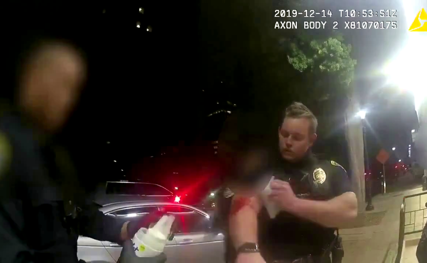 San Diego Police Officer Dillon Fuston wipes blood off his arm after he held down a man who'd been stabbed, Dec. 14, 2019.