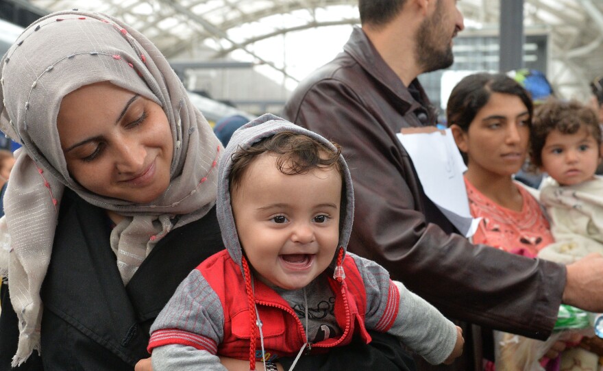 A woman holds her smiling baby in her arms as she arrives at the Hauptbahnhof station in Salzburg, Austria, on Saturday on their way with other migrants from Hungary via Vienna to Germany.