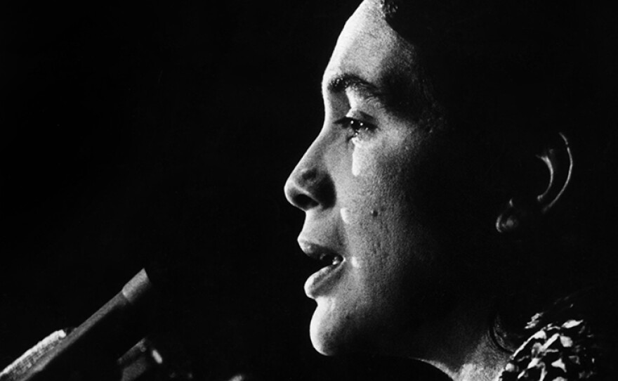 Dolores Huerta speaks at the podium, c1970s.