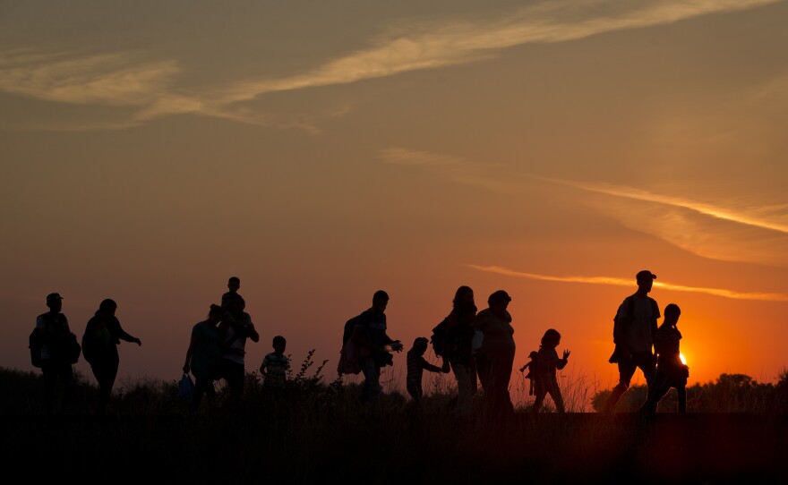 Refugees from the Middle East are silhouetted against the setting sun as they walk on railway tracks from Serbia, in Roszke, Hungary, on Sunday.