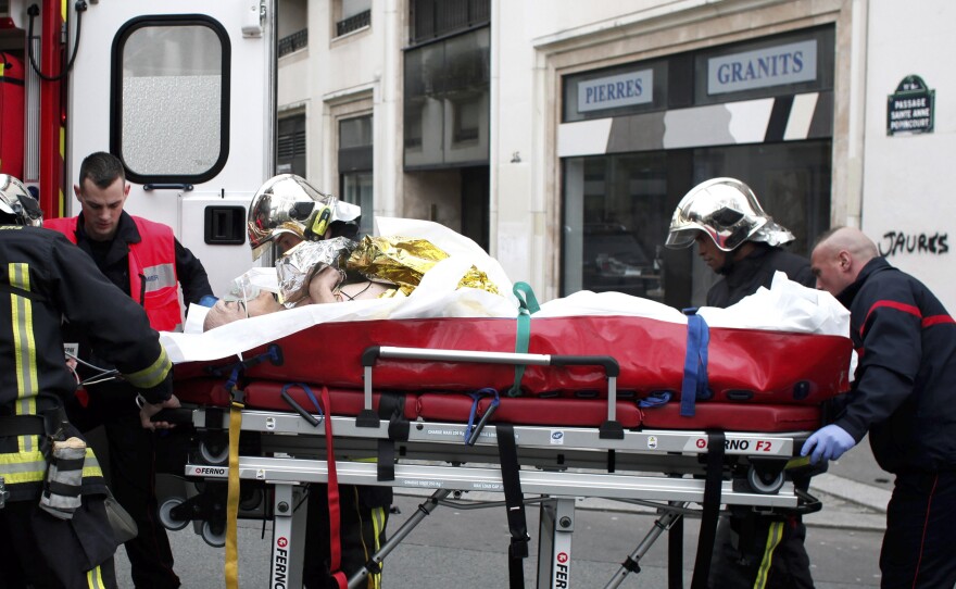 An injured person is transported to an ambulance after a shooting at the French satirical newspaper Charlie Hebdo's office in Paris, Jan. 7, 2015.