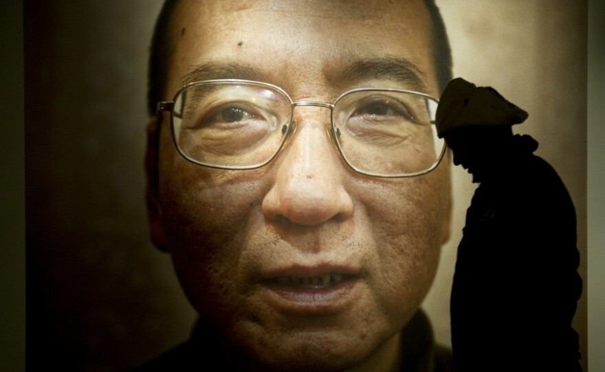A man walks in front of a poster of Chinese dissident and Nobel Peace Prize laureate Liu Xiaobo at an exhibition in Oslo. Liu remains in a Chinese prison, and the ceremony has infuriated China's authoritarian government, while presenting it with public relations problems over its human-rights record.