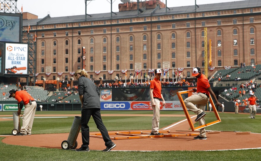 Groundskeepers prepare the infield before an opening-day baseball game between the Minnesota Twins and the Baltimore Orioles on Thursday in Baltimore.
