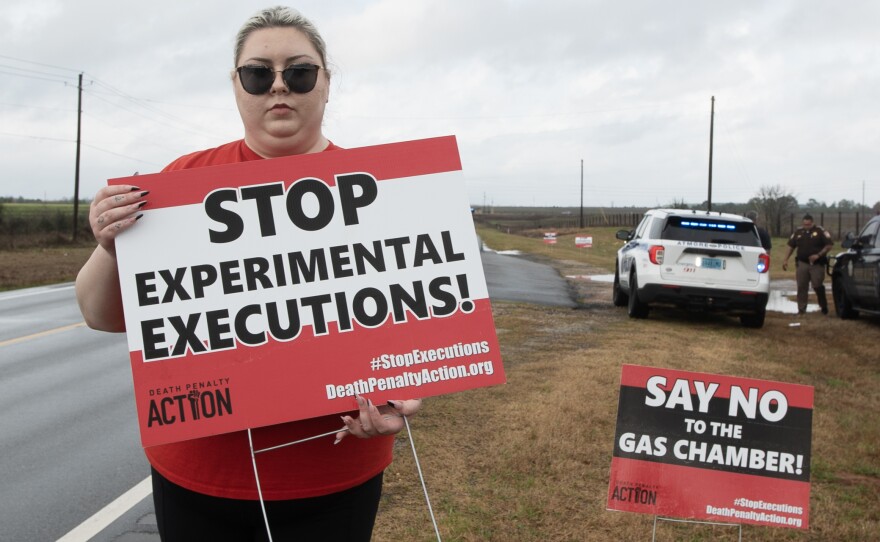 Alli Sullivan holds a sign protesting the use of nitrogen gas in executions on the road leading to Holman Correctional Facility in Atmore, Ala. She is on the communications team at Death Penalty Action, an organization that seeks to stop executions and end the death penalty.