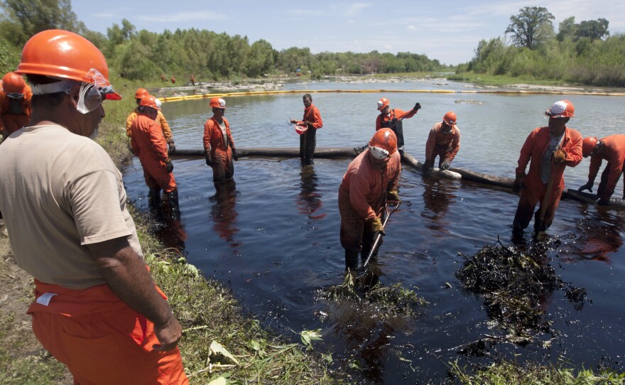 Workers from Pemex clean the San Juan river after an oil spill caused by fuel pirates who tapped into a pipeline in Nuevo Leon state, Mexico, in August 2014. Fuel pirates are one of many above-ground complications in opening up the oil fields of northern Mexico.