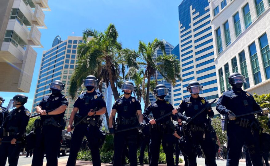 A line of police officers observe protesters during a demonstration in downtown San Diego, May 31, 2020.