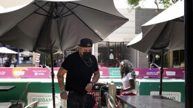 A waiter wears a face mask while tending to customers amid the COVID-19 pandemic Tuesday, May 18, 2021, in Burbank, Calif. 