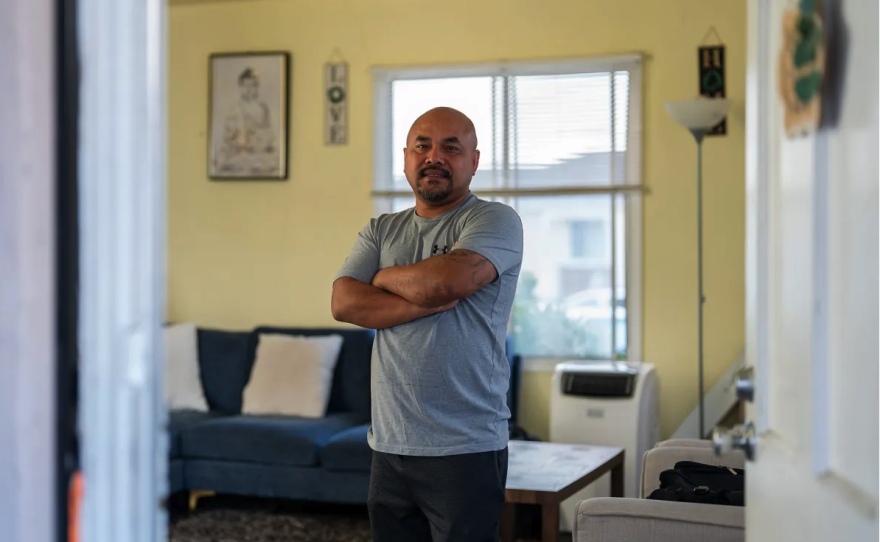 Chanthon Bun se encuentra en la sala de estar de su casa en San Leandro el 23 de noviembre de 2024. Bun nació en Camboya durante el genocidio de la década de 1970 y creció en un campo de refugiados en Tailandia antes de mudarse a los Estados Unidos, donde fue condenado por robo a los 18 años. Eso fue hace décadas, pero ahora está ansioso por el plan del presidente electo Donald Trump para la deportación masiva de inmigrantes. Foto de Jungho Kim para CalMatters