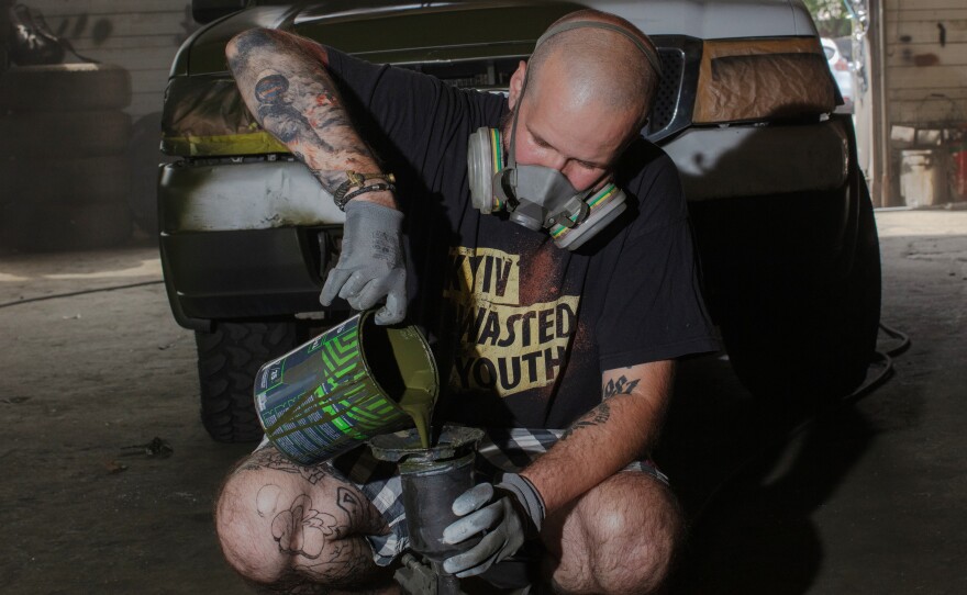 <em>Neak, a 43-year-old Ukrainian graffiti artist, mixes green paint at a workshop in Kyiv, Ukraine. His ETC graffiti crew works to camouflage cars to be sent east to the front line of the war with Russia.</em>