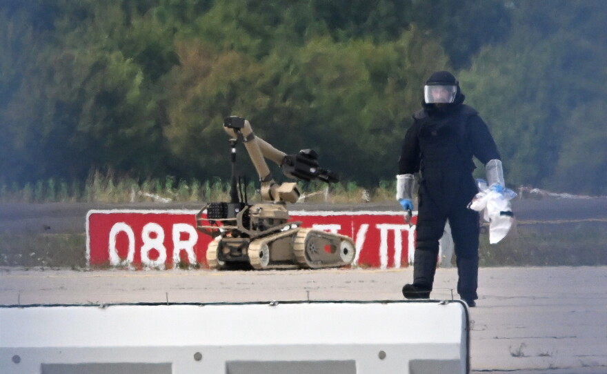 A forensic technician works alongside a bomb-disposal robot near a Ukrainian aircraft at Leipzig/Halle Airport, where a drone with an explosive device was found and a detonator was removed from the object, in Schkeuditz, Germany, Wednesday Aug. 5, 2026.