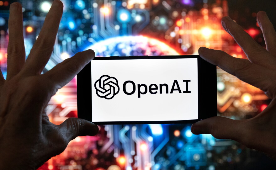 FILE - The OpenAI logo is displayed on a cell phone in front of an image generated by ChatGPT's Dall-E text-to-image model, Dec. 8, 2023, in Boston.