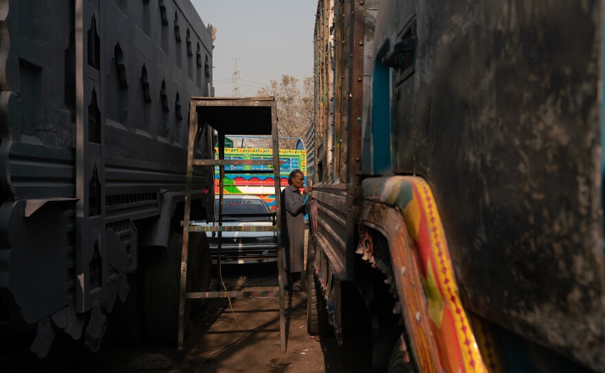 In a Rawalpindi truckyard, the trucks are lined up next to each other awaiting the attention and repairs of the mechanics and artists working there.