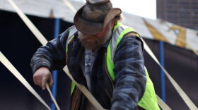 Assistant tent master Michael LeClaire secures the Big Apple tent.