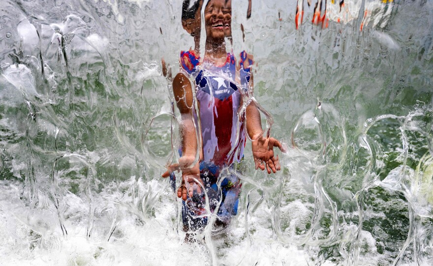 A summer of extreme heat is raising alarms of health risks. Here, a child plays in a waterfall feature at Yards Park in Washington, D.C., on June 26.